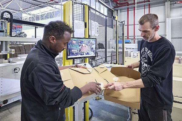Mitarbeitende prüfen eine Verpackung.